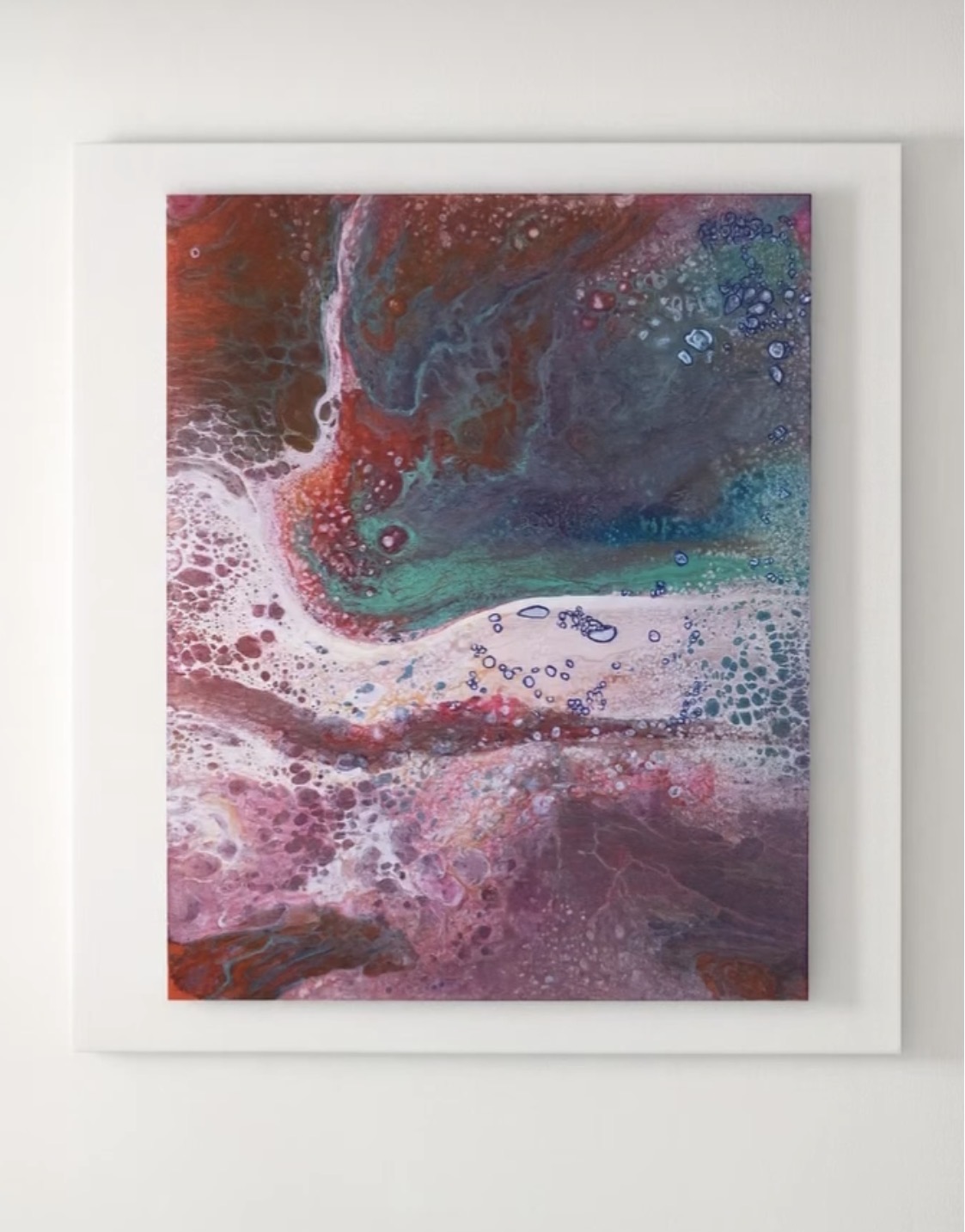 Abstract painting of flowing rust red, violet and turquoise with white cells and bubbles, hung on a white wall